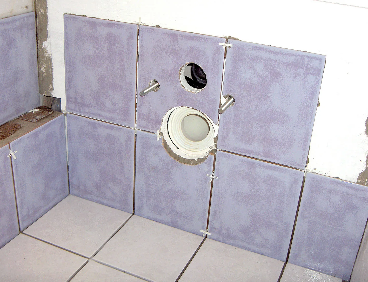 Pose de carrelage au sol, carreaux alignés sur un lit de mortier